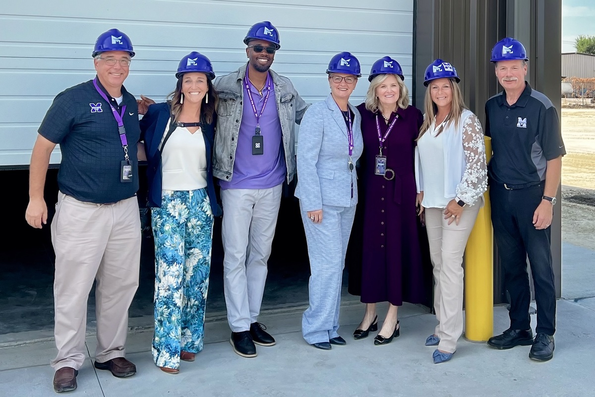 Group of 7 people posing for picture with hard hats on